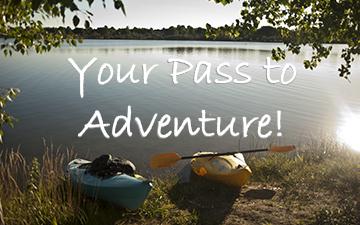Kayak and gear on a lakeshore at sunrise with 'Your Pass to Adventure!' text overlay.